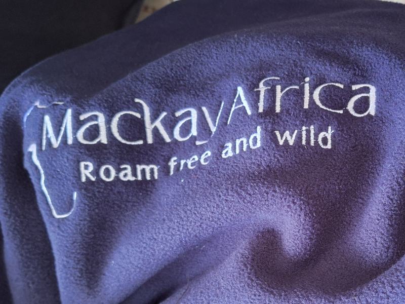 A safari company's name embroidered in white on the navy fleece side of a kanga blanket