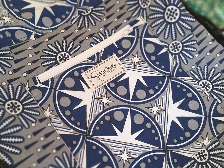 A small woven label sewn onto the pocket of a navy star-print kanga bag