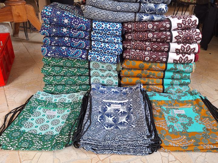 Rows of finished gift sets folded and stacked by colour, with their bags laid out in front