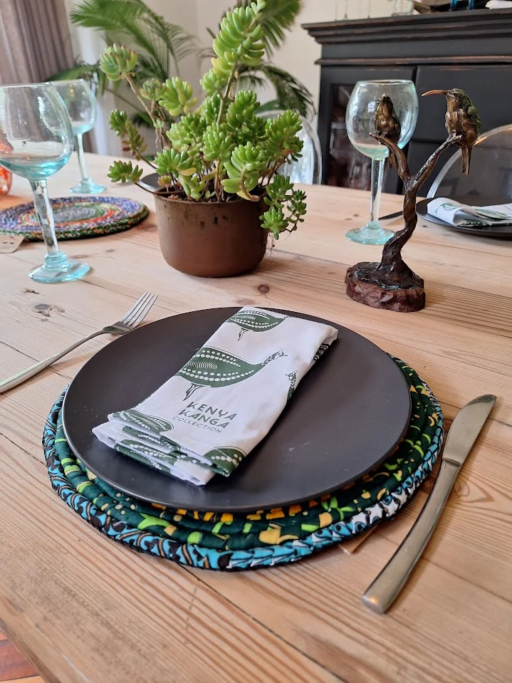 A table set with a guinea fowl print napkin on a dark plate over round fabric placemats